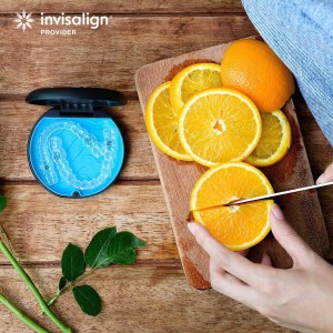 oranges being sliced on a cutting board with an Invisalign container next to it